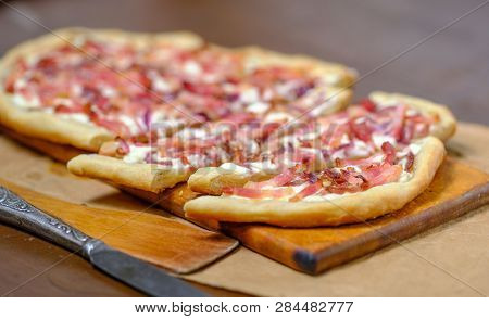 Alsatian Tart Flambé Or Flammkuchen With Bacon And Onions On A Dark Table.