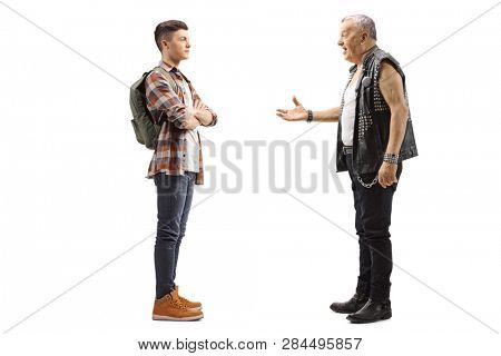 Full length profile shot of an elderly male punker talking to a young teenage male student isolated on white background
