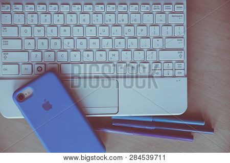 Laptop Kayboard And Apple Cellphone On The Desk. Urban Home Design Photo.
