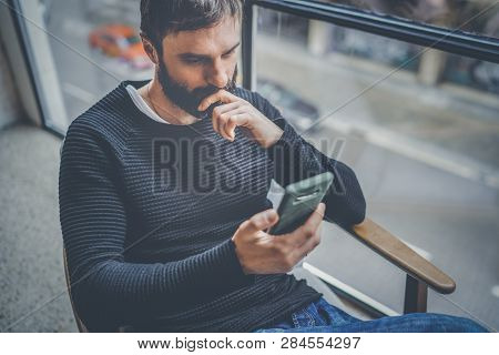 Bearded Hispanic Man In Black Pullover Using Mobile Phone Application For Mobile Blog. Confident You