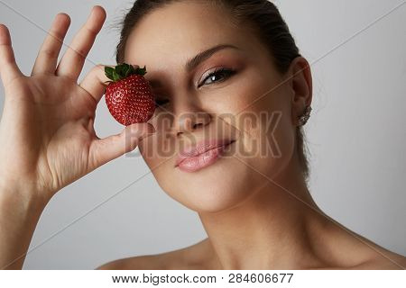 Portrait Of Handsome Young Women Smiling And Holding Hand Fresh Strawberry Close Her Eyes Over Gray 