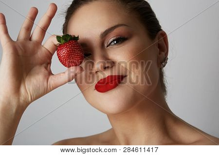 Portrait Of Handsome Young Women Smiling And Holding Hand Fresh Strawberry Close Her Eyes Over Gray 