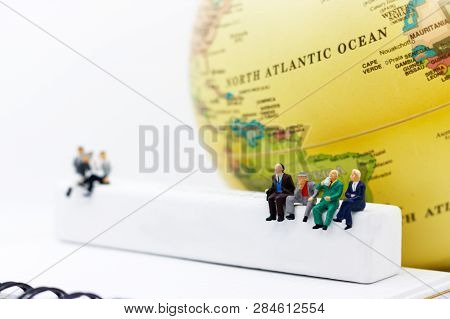 Miniature People: Business Team Reading Book On White Wooden Box With Globe. Education Or Business C