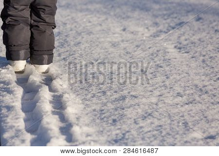 A Small Child Goes Through The Snow And Leaves A Chain Of Traces. The Concept Of Small Steps Forward