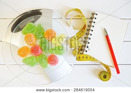 Fruit Jelly On Kitchen Scales Next To A Notebook, A Pen And A Tape Measure. Counting And Recording T