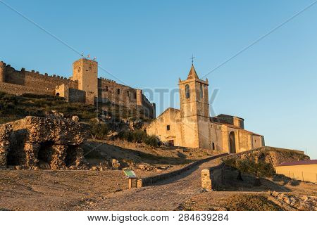 The Church Of Santiago Apostol And The Castle Of Medellin Seen At Sunset, Extremadura, Spain.