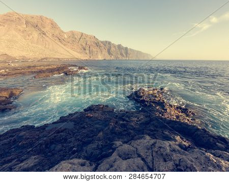 Waves Splashing Into Volcanic Coast At Sunset.