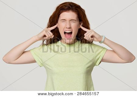 Stressed Angry Redhead Woman Sticking Plug Fingers In Ears Screaming