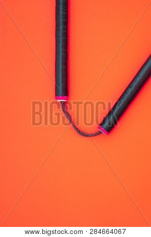 Training Black Nunchaku Is Isolated On A Red Background.