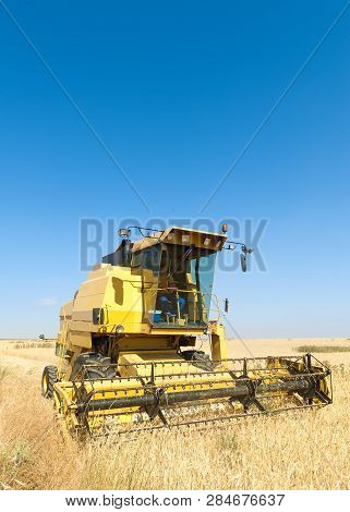 Agricultural Machinery Working On The Barley Tour With Sunny Day
