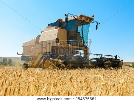 Agricultural Machinery Working On The Barley Tour With Sunny Day