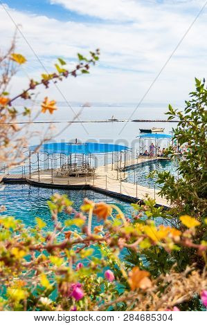 Eilat, Israel - March 21, 2017: Southern Plants Close-up With On Water Pavilions And Wooden Walkways