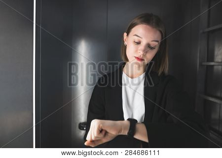 Punctual Office Worker Is Checking Time In The Lift. Young Woman Is Watching Her Clock To Check Time