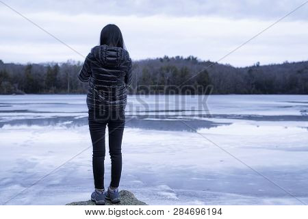 A Chinese Woman Wearing A Winter Coat Overlooking The Frozen Waters Of Burr Pond State Park In Torri