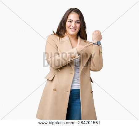 Beautiful plus size young woman wearing winter coat over isolated background In hurry pointing to watch time, impatience, upset and angry for deadline delay