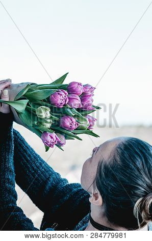 Pretty Woman Holding A Bouquet Of Pink And Green Tulipflowers In Her Hands, Up In The Air Against Th