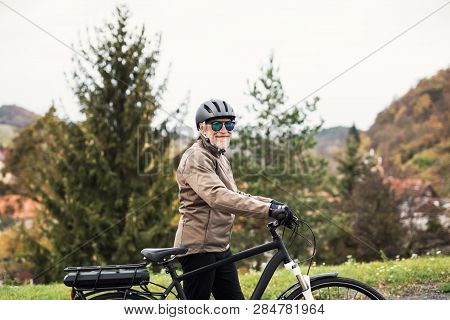 Active Senior Man With Electrobike Standing Outdoors On A Road In Nature.