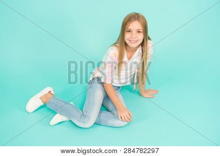 Girl Happy Face Sit On Floor Attentive Looking At Camera Turquoise Background. Kid Girl With Long Ha