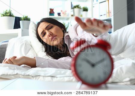 Sleepy Young Woman Portrait With One Opened Eye Trying Kill Alarm Clock. Early Wake Up Not Getting E