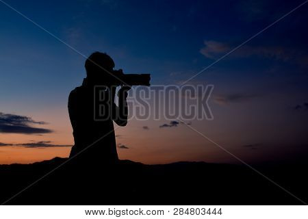 Silhouette Of A Man Who Is Professional Photographer Is Using A Dslr Camera At Twilight,orange And B