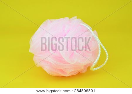 Pink Plastic Body Scrubber On Yellow Paper Background.a Kind Of Medical Device For Cleaning The Body