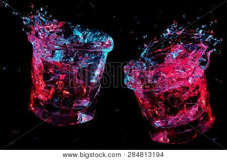 Liquid Flying From Two Full Rocks Glasses Which Have Just Toasted Under Colorful Lights Isolated On 
