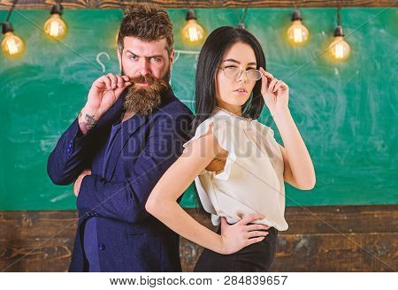 Man With Beard And Teacher In Eyeglasses Stand Back To Back, Chalkboard On Background. Lady And Hips