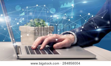 Businessman typing on laptop with linked reports charts grapghs around