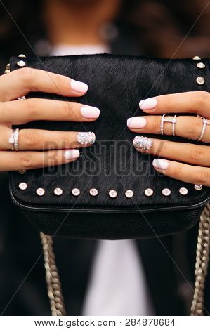 Girl With Manicured Nails With Beautiful Ornament In Wedding Rings Holding Black Fur Bag.
