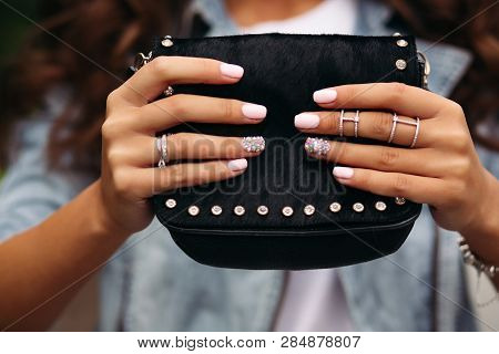 Girl With Manicured Nails With Beautiful Ornament In Wedding Rings Holding Black Fur Bag.