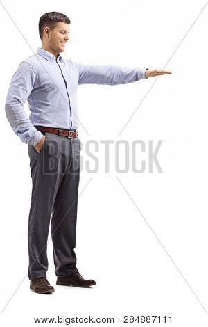 Full length shot of a young man in formal clotes gesturing with hand and showing the height of something isolated on white background