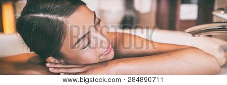 Woman taking hot bath at home panoramic banner. Asian girl relaxing in bathtub sleeping happy panorama. Wellness alone time. lady happy sleeping in luxury spa hotel room lifestyle.