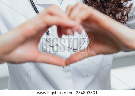 A Young Woman Doctor Is On A Gray Background. During This Time, The Heart Symbol Shows On The Chest 