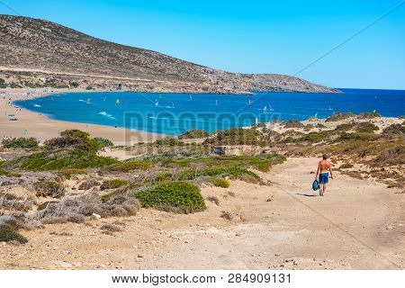 Man Walking To Prasonisi Beach Full Of Windsurfers (rhodes, Greece)