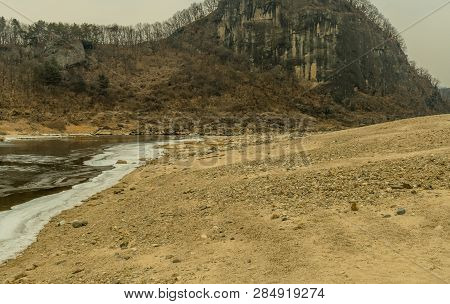 Sandy Beach On Frozen River In Front Of  Jwasangbowi Rock; A Large Volcanic Rock In  Jangtan-ri, Sou