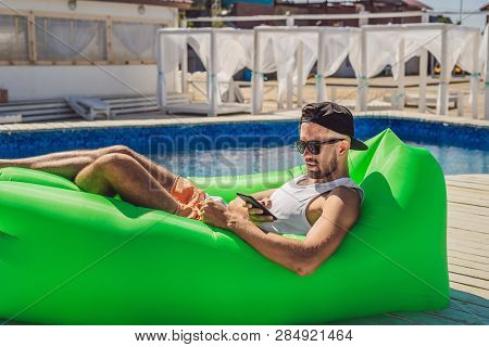 Young Man Enjoying Leisure, Lying On The Air Sofa Lamzac, Near The Pool