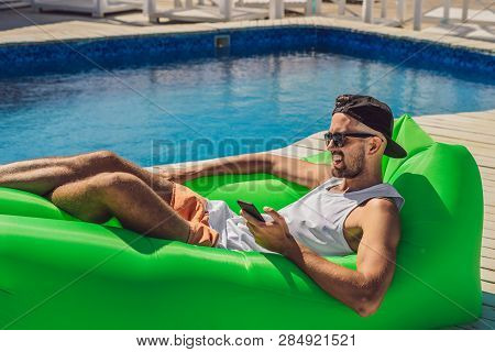 Young Man Enjoying Leisure, Lying On The Air Sofa Lamzac, Near The Pool