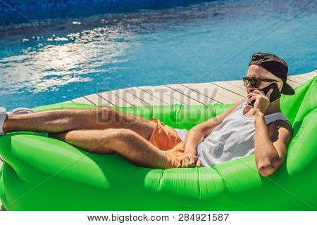 Young Man Enjoying Leisure, Lying On The Air Sofa Lamzac, Near The Pool