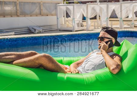 Young Man Enjoying Leisure, Lying On The Air Sofa Lamzac, Near The Pool