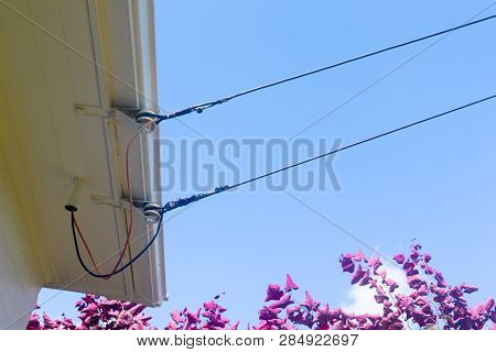 Old-fashioned Power Lines Providing Electricty Access Via Insulator To Surfiet Of House Close-up