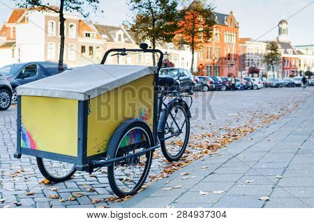 Dutch Yellow Cargo Pedal Tricycle Parked Near Sidewalk On The Street Of Leiden, Netherlands. Histori
