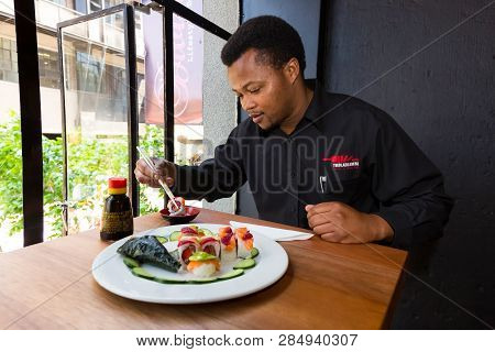 Johannesburg, South Africa - September 28 2014: African Man Eating Sushi In A Restaurant