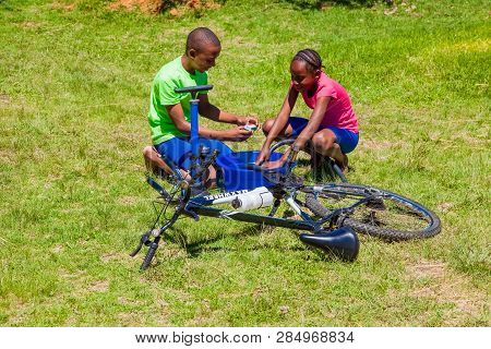 African Children Fixing A Puncture On A Bike
