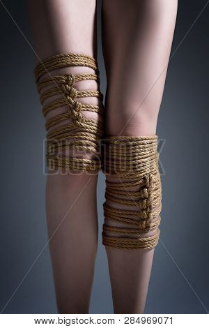 Young Seductive Slim Woman Lying On Mirror Floor Tied With Decorative Knots Of Natural Jute Rope. An