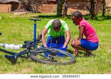 African Children Fixing A Puncture On A Bike