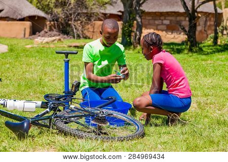 African Children Fixing A Puncture On A Bike
