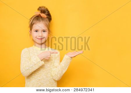 A Cute Little Girl Is Attracted By Attention Pointing A Finger At Something. The Concept Of Advertis