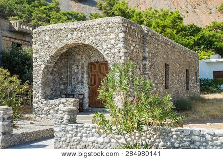 Old Small Brick Cube Shape House With Wooden Door. The House In The Greece Countryside.