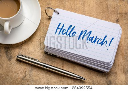 Hello March! Handwriting on a stack of index cards with a cup of coffee and  a pen