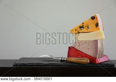 Different Types Of Delicious Cheeses And Fork On Slate Plate. Space For Text